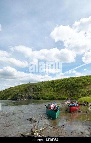 Due spiaggiata canoe su un telecomando, scenic alaskan banca di fiume con una soleggiata cielo blu in un ritratto verticale. Foto Stock