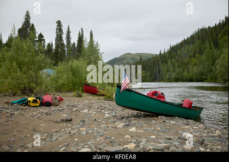 Due spiaggiata canoe a riverbank campeggio durante un'avventura su un wild alaskan river. Foto Stock