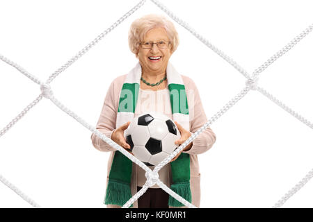 Femmina anziani tifoso di calcio con una sciarpa e un calcio dietro una rete isolata su sfondo bianco Foto Stock