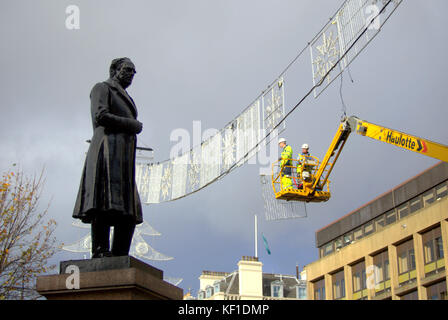 Gli operai del Consiglio segnalano l'arrivo delle festività natalizie mentre preparano le decorazioni per le luci natalizie nella George Square della città. Foto Stock