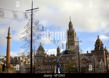 Gli operai del Consiglio segnalano l'arrivo delle festività natalizie mentre preparano le decorazioni per le luci natalizie nella George Square della città. Foto Stock