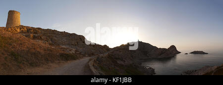 La Corsica e Ile Rousse (isola rossa): tramonto sulla torre genovese e la pietra faro sulla parte superiore dell'Ile de la pietra (stone island) promontorio Foto Stock