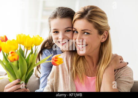 Felice ragazza dando ai fiori di madre a casa Foto Stock