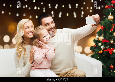Famiglia tenendo selfie con lo smartphone a natale Foto Stock
