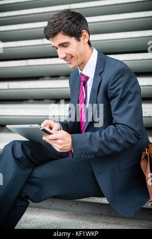 Imprenditore utilizzando una pastiglia per la comunicazione o di archiviazione dei dati fuori Foto Stock