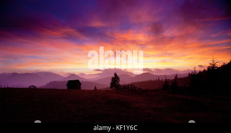 Bellissimo tramonto alpino con abeti e cottage Foto Stock