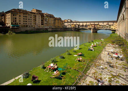 Firenze, Toscana - aprile 09, 2011 - ponte vecchio sul fiume Arno e il verde dei prati per prendere il sole Foto Stock