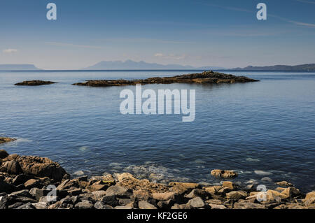 Sunny summer view attraverso il mare da Scottish West Highland costa a mallaig con rocce, cielo blu e le montagne in lontananza delle Western Isles Foto Stock