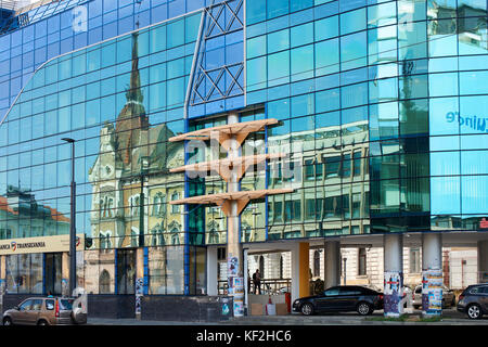 Moderno in vetro-edificio frontale (Banca Transilvania) in Cluj con riflessioni di vecchi edifici in Windows Foto Stock