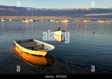 Piccole derive floating al di ancoraggio nella tranquilla marina al tramonto Foto Stock