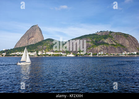 Morro da Urca e Pao de Acucar (Sugarloaf montagna) con una barca a vela, Rio de Janeiro, Brasile Foto Stock