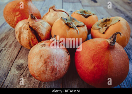 Cachi freschi , zucca e melograno frutto su una tavola di legno Foto Stock