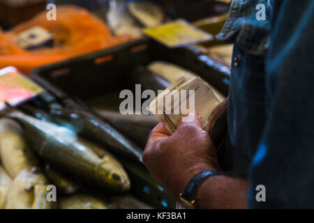 Close-up di carta croato note (chiamati kuna), che viene fatto passare attraverso una scatola di pesce presso il trafficato mercato del pesce in Split, Croazia. Foto Stock