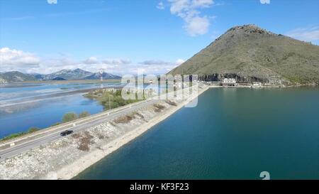 Nero auto la guida sul ponte blu del mare, delle montagne e del cielo sfondo. riprese. vettura andando su una strada vicino al fiume, vista aerea. le riprese. vista aerea al piccolo lago di foresta e la linea di autostrada passando vicino a. Foto Stock