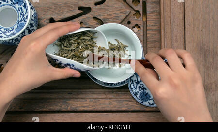 Riempire una teiera marrone attraverso un imbuto. Tazze cinesi in porcellana, cucchiaino in acciaio. Nero, verde, puerh, oolong, tieguanyin, sencha, tè Foto Stock