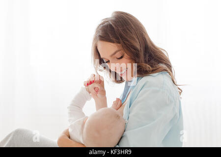 Donna sorridente con il bambino su uno sfondo bianco Foto Stock