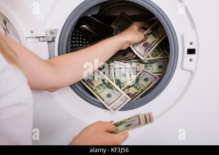 Close-up di persona mano inserire il denaro sporco in lavatrice Foto Stock