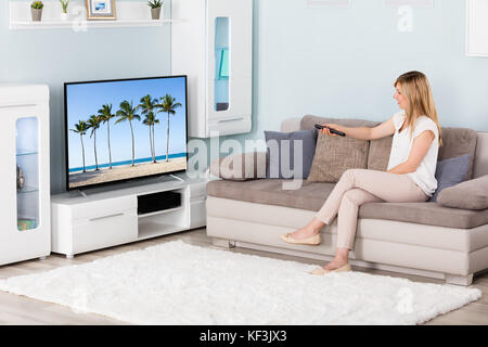 Giovane donna guardando film in televisione a casa Foto Stock