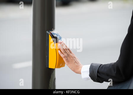 Close-up di imprenditrice mano gialla di pressatura pulsante crosswalk Foto Stock