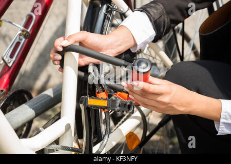 Close-up di imprenditrice di bloccaggio a mano la sua bicicletta Foto Stock