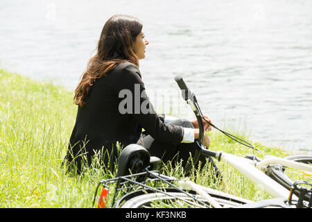 Giovane imprenditrice seduta dal lago vicino a noleggio Foto Stock