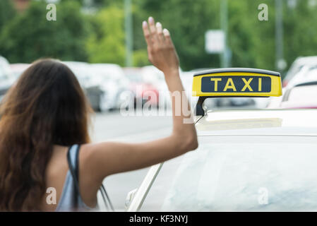 Close-up di una donna che chiama per taxi Foto Stock