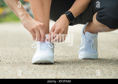 Close-up di atleta femminile cercando le scarpe running ottenere pronto per jogging Foto Stock