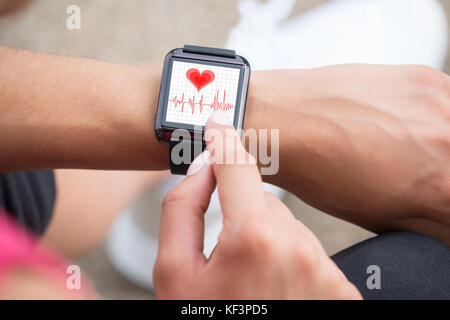 Close-up della mano umana indossando Smart Guarda che mostra la frequenza cardiaca Foto Stock