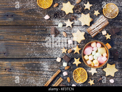 Natale gingerbread cookies stelle su un tavolo di legno con cannella e noci, fettine di arancia e cookie cutter, il fuoco selettivo Foto Stock