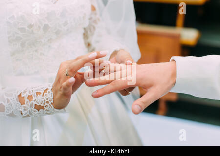 Close-up foto di mani della sposa di mettere le nozze anello al dito dello sposo. Foto Stock