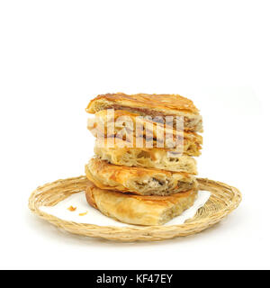 Varietà di gusto pila di croccante burek o la torta su un tovagliolo di carta in una in vimini o cestino per pane su sfondo bianco Foto Stock