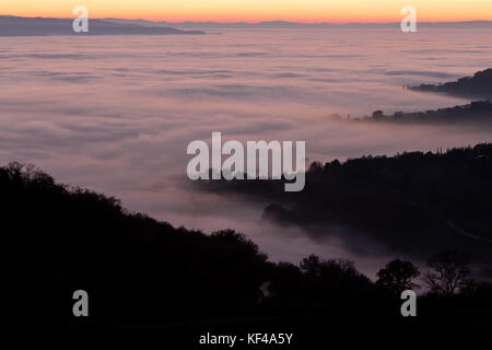Vista aerea di una valle piena di nebbia al tramonto, con bei colori caldi del cielo riflettendo su la nebbia Foto Stock