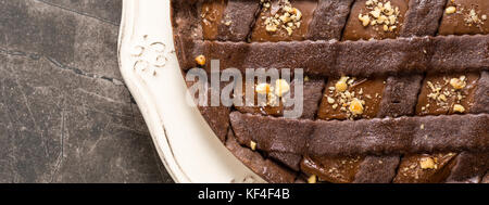 Torta al cioccolato torta guarnita con le nocciole su pietra scura sullo sfondo della tabella Foto Stock