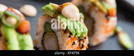 Sushi fresco rotoli servita su pietra scura piastra. Set di Sushi con aragosta, Avocado, caviale e sesamo nero. Cucina tradizionale giapponese. Foto Stock