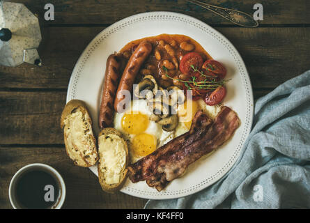 Prima colazione Inglese con uova fritte, salsicce, funghi, pancetta, fagioli, caffè Foto Stock