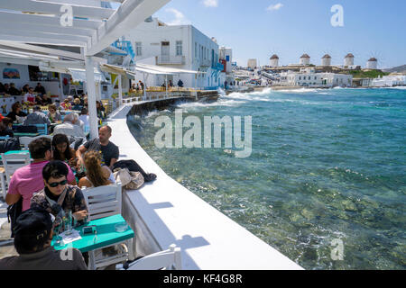 Turisti in un ristorante con vista ai famosi mulini a vento, Little Venice, Mykonos-town, Mykonos, Grecia Foto Stock