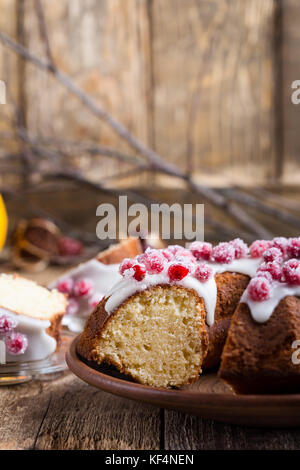 I canditi di mirtilli bundt torta al limone con glassa di zucchero sulla tavola di legno. in casa autunno e inverno vacanza piacevole dessert su tavolo rustico Foto Stock