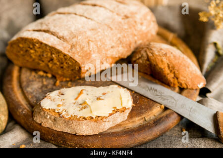 Close up del pane di segale coperto con il burro sulla tavola di legno prima colazione concept Foto Stock