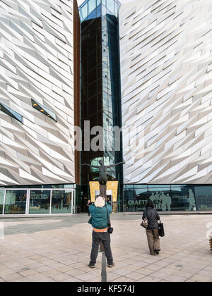 Un uomo fotografa la scultura Titanica, di Rowan Gillespie, di fronte al Titanic Belfast Foto Stock