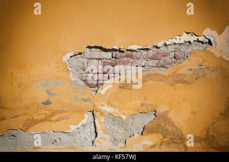 Brickwall danneggiato con un foro. danneggiati sul gesso brickwall. vecchio muro in mattoni con intonaco danneggiato square. effetto vignetta Foto Stock