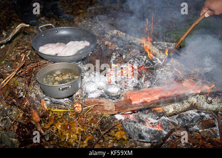 Fresco di filetti di pesce la frittura in padella con le vongole bollite e patate al forno a fuoco di campo Foto Stock