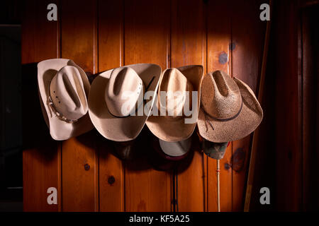 Quattro cappelli da cowboy appeso in fila su pannelli in legno parete Foto Stock