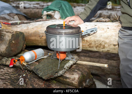 Uomo di acqua bollente utilizzando camping fornello a gas Foto Stock