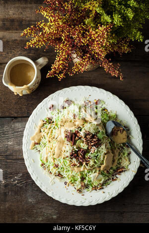 Cesare gourmet con lattuga, parmigiano grattugiato, noci pecan tostate e vinaigrette di senape Foto Stock