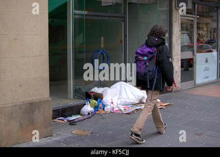 Glasgow giovani senzatetto ragazzo morto guarda come egli dorme sul terreno in porta inconscio come stranieri a piedi da sulla strada di piumone Foto Stock