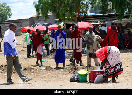 Maasai tribesmen in un colorato bovini e prodotti freschi di mercato nel nord della Tanzania. Foto Stock