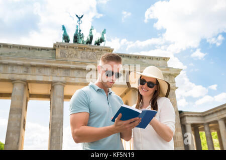 Coppia giovane lettura guida turistica nella parte anteriore della porta di Brandeburgo Foto Stock