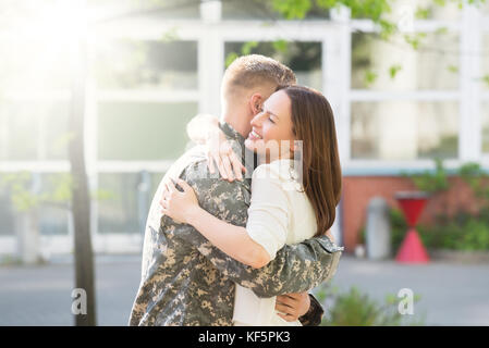 Ritratto di Felice moglie abbracciando il marito in uniforme militare Foto Stock