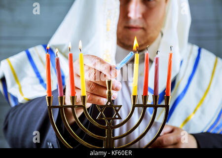 Man mano le candele per illuminazione in menorah sulla tavola è servita per hanukka uomo candele luci Foto Stock