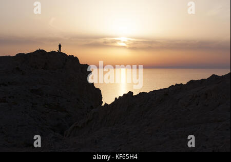 Corsica: la gente guardando il tramonto sul mar Mediterraneo dalla parte superiore dell'Ile de la pietra (stone island), il promontorio di Ile Rousse (isola rossa) Foto Stock